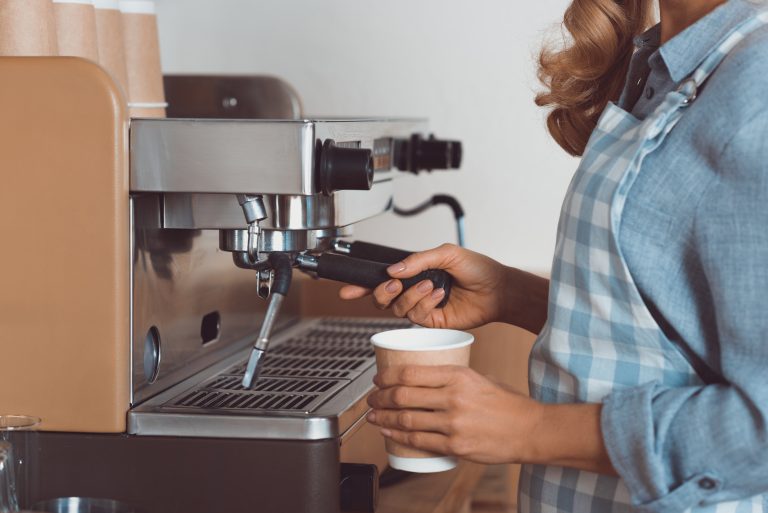 Funcionária prepara café em máquina de cafeteria