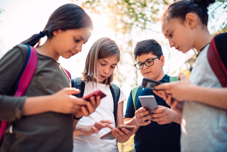 Crianças reunidas mexendo no celular