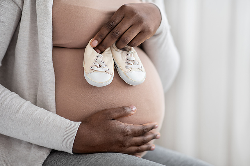 Mulher negra gravida, segura sapatinhos de bebe. close